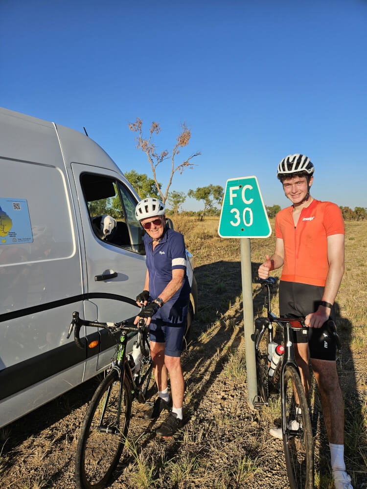 Bob Montgomery and Tom Malcolm beside an FC 30 road marker with their bicycles
