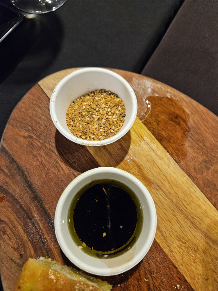 Dinner in Fitzroy Crossing Bread with bowls of olive oil and dukkah on a wooden table