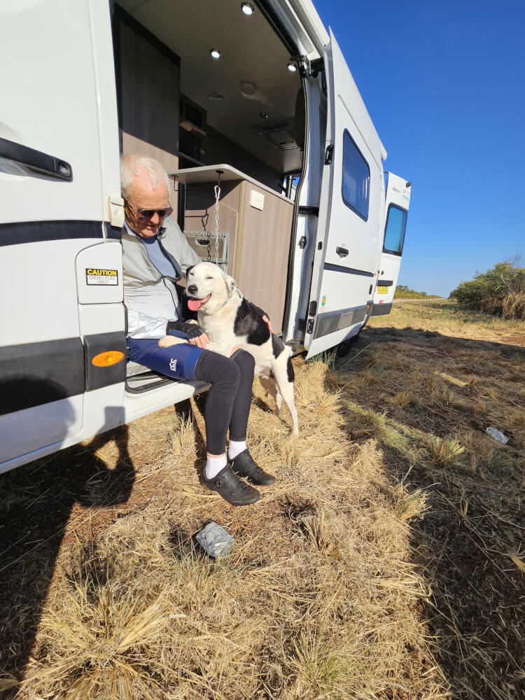 Bob and Lucky Bob Montgomery sitting beside the support van cuddling Lucky the dog
