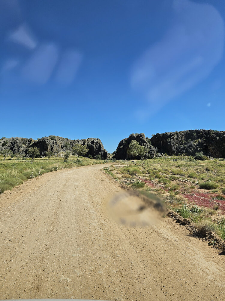 Into Mimbi Campground Gravel road winding between rocky formations at Mimbi Caves