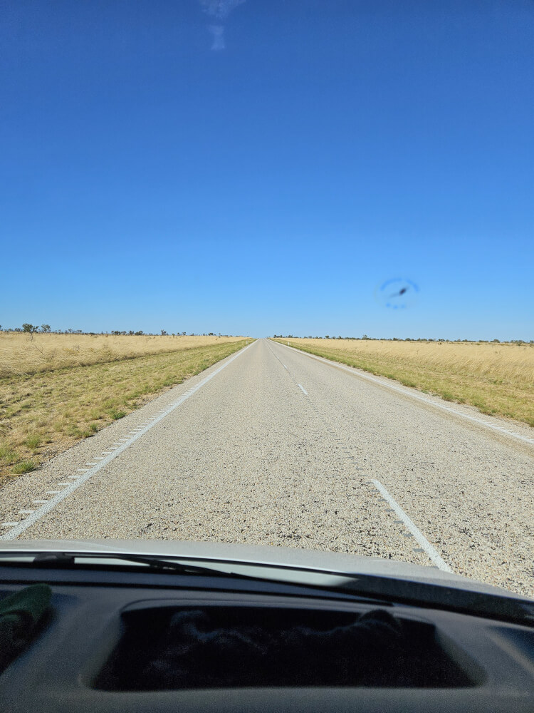 Open Kimberley Country Straight highway through flat dry grassland under a blue sky
