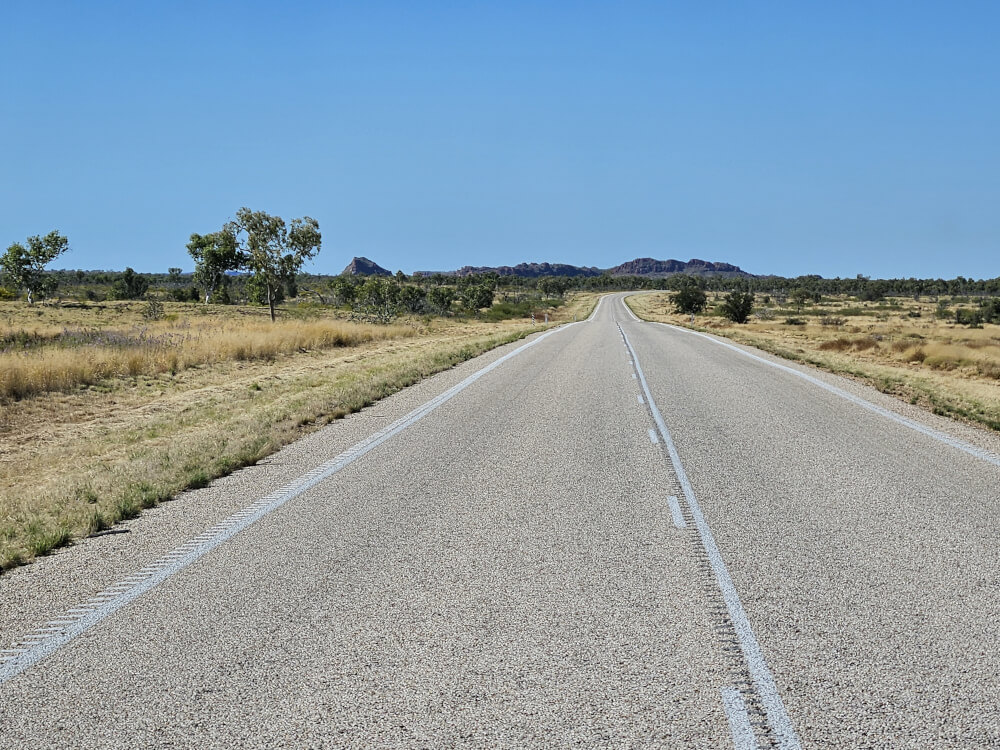 Kimberley Rock Country Large dark rock formation rising from grassland beside the highway