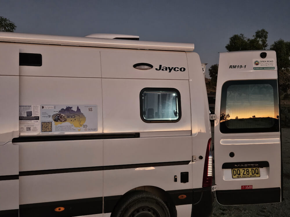 Sunrise Reflections on the Vans Early morning light reflected in the windows of the support vans at Mimbi Caves