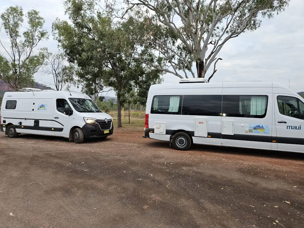 Finding the Diesel Bowsers | Victoria River Roadhouse Two white campervans parked together beneath gum trees near the diesel refuelling area at Victoria River Roadhouse.