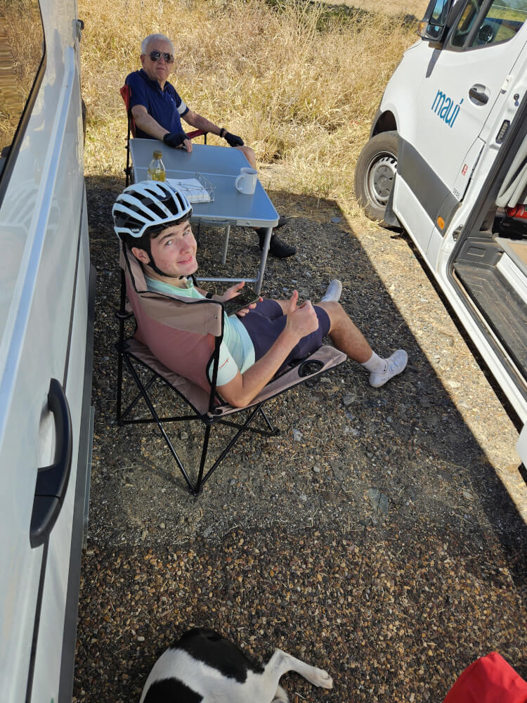 Finding Shade in 37 Degree Heat Bob and Tom resting in the shade between the support vans with Lucky nearby