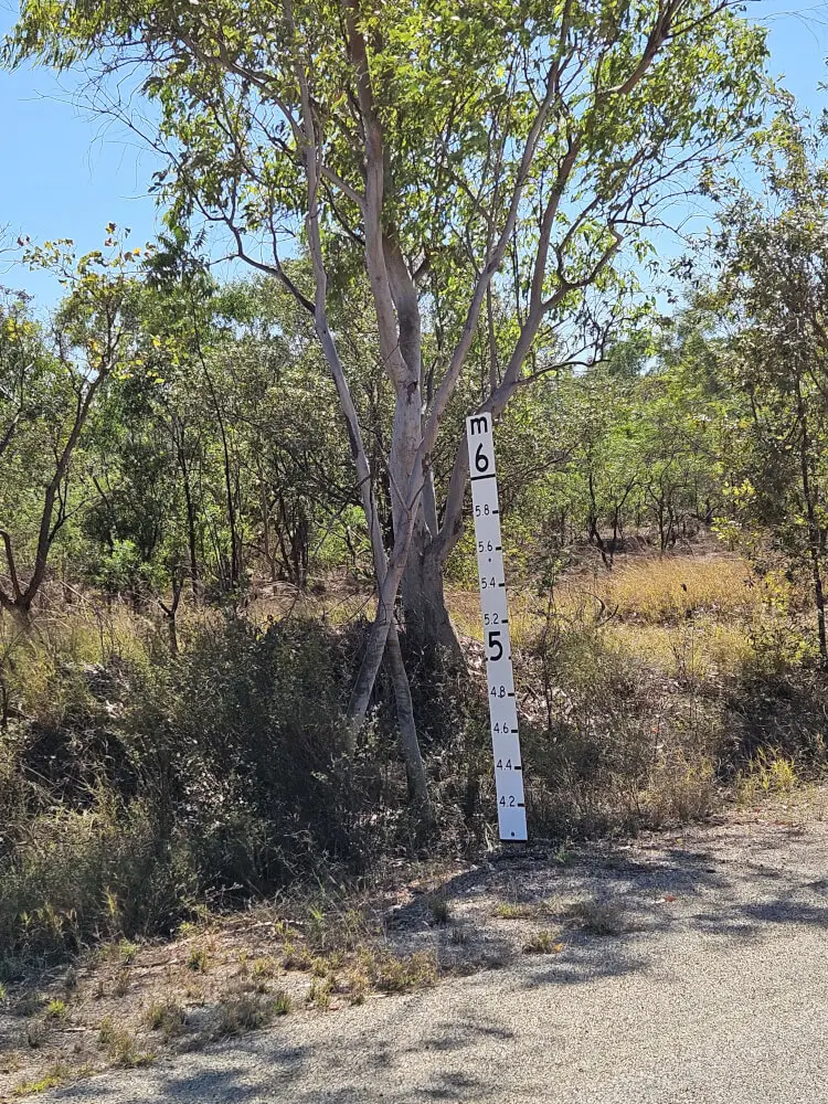 Flood Level Marker at Nitmiluk Tall white flood level gauge marked from 4.2 to 6 metres standing beside a tree