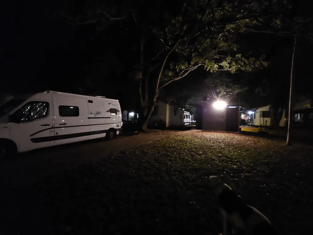 Camping at Knotts Crossing White campervan parked beneath trees at a campground after dark