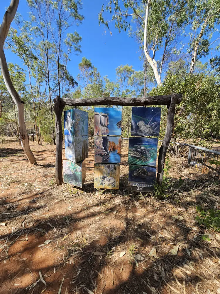 Wildlife Art at Nitmiluk Painted panels depicting native wildlife hanging from a timber frame among trees at Nitmiluk National Park