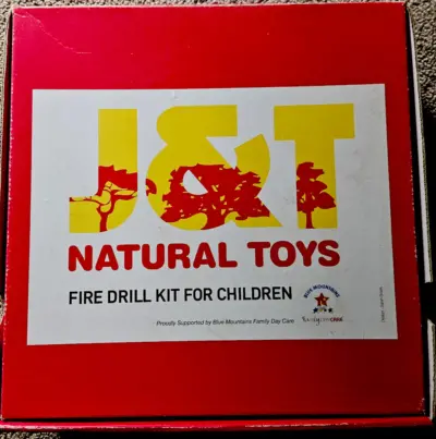 Original red J & T Natural Toys Fire Drill Kit box featuring the logo and label designed by Sarah Brook.